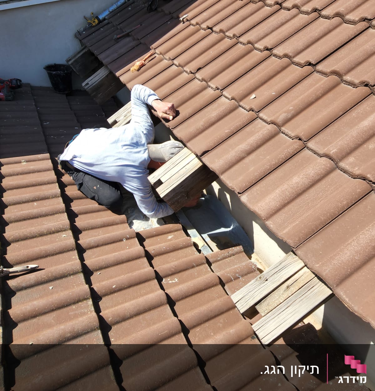 אדם מתקן רעפים על גג חום עם כלים